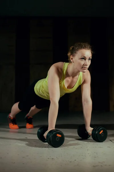 Deportiva chica es exprimido con mancuernas en el gimnasio — Foto de Stock