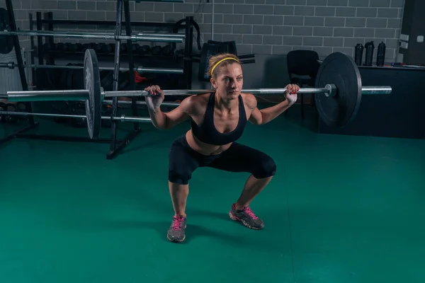Crossfit Muscular mujer fuerte agacharse con peso pesado en el gimnasio — Foto de Stock