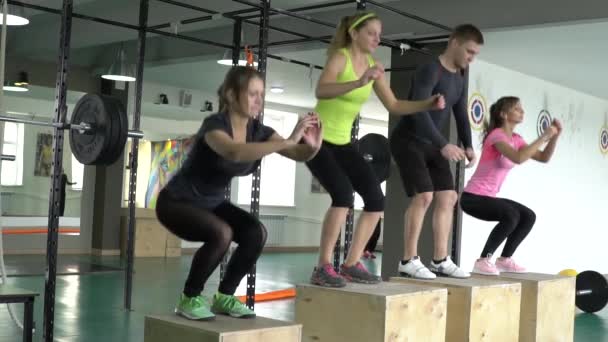 Un gruppo di sportivi in palestra salta su scatole di legno. In forma. Sport attivo — Video Stock