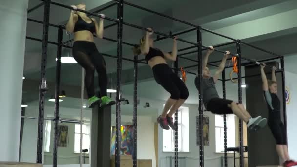 Een groep jonge mensen doen pull-ups op de balk in de sportschool. Slow motion — Stockvideo