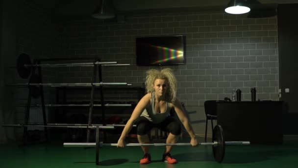 Una hermosa chica deportiva levanta un peso pesado en el gimnasio. Movimiento lento — Vídeos de Stock