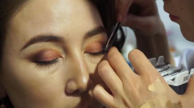 Makyaj sanatçısı yapay kirpikleri yetişkin bir kadın gözünü koyar. Kozmetik kirpik uzatma