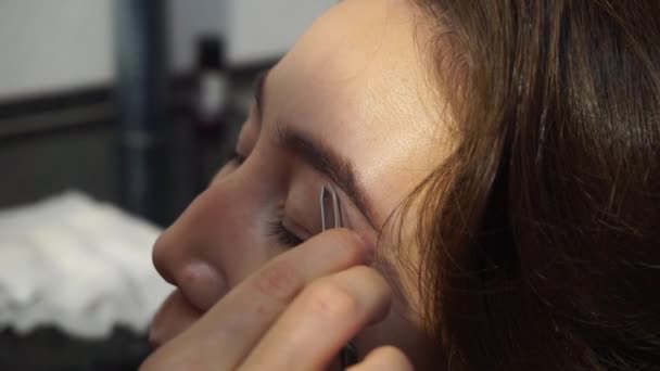 Corrección de cejas. El estilista arranca las cejas de una mujer adulta, corrige la forma de las cejas. Cuidado facial — Vídeos de Stock