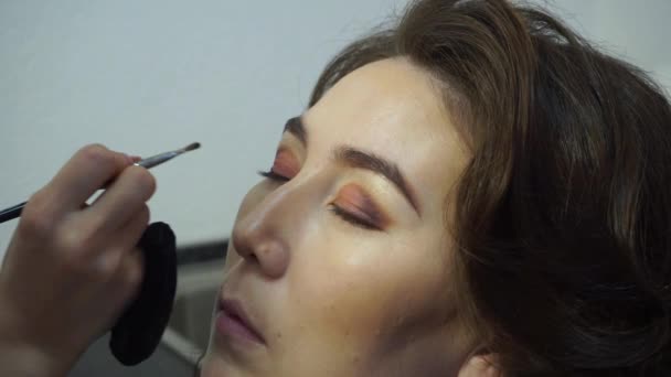 Μακιγιάζ για μια ώριμη γυναίκα. Η make-up artist βάζει σκιές στα βλέφαρα μια γυναίκα της Ασίας εμφάνισης — Αρχείο Βίντεο