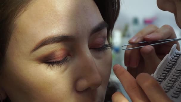 Extension de cils. Un maquilleur applique des cils à une femme kazakhe mature — Video