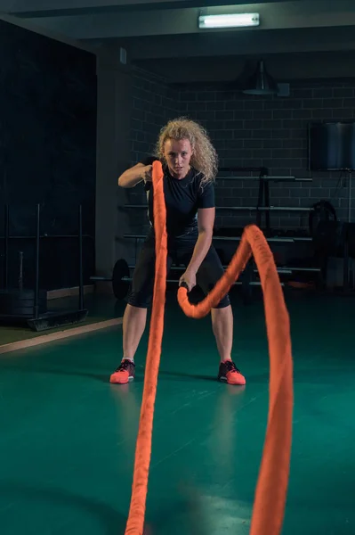 Mujer fuerte joven está entrenando con cuerdas marciales en el gimnasio . — Foto de Stock