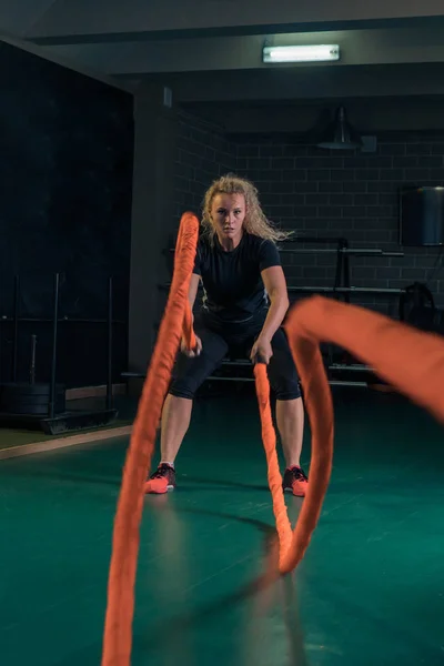 Mujer fuerte joven está entrenando con cuerdas marciales en el gimnasio . —  Fotos de Stock