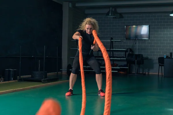 Mujer fuerte joven está entrenando con cuerdas marciales en el gimnasio . — Foto de Stock