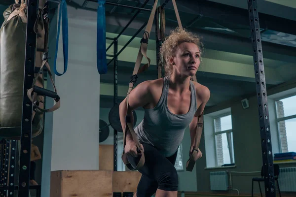 Ejercicios de fuerza. Una chica está haciendo un ejercicio en los músculos de la espalda en el gimnasio — Foto de Stock