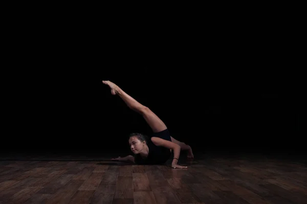 Flexible girl doing a gymnastic exercise on a black background. Sport. Fitness. Stretching. — Stock Photo, Image