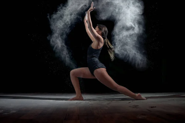 Танцююча дівчина з борошном на чорному тлі — стокове фото