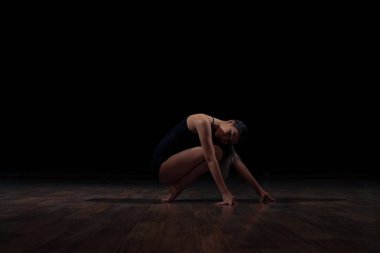 Esnek kız siyah bir zemin üzerine jimnastik bir egzersiz yapmak. Spor. Fitness. Germe.
