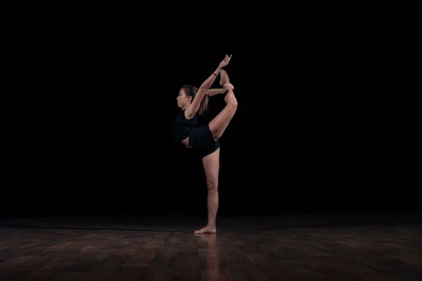 Молода дівчина-гімнастка ізольована на чорному фоні робить гімнастичний ескіз — стокове фото