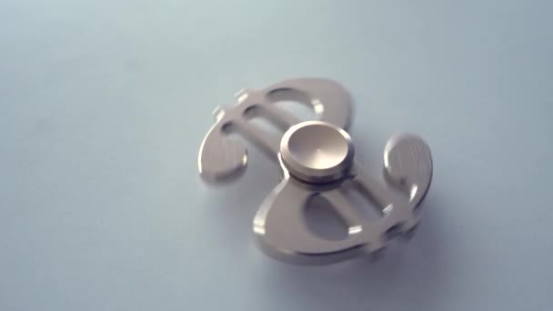 Drehung des Spinners in Form eines Dollars auf einer leichten Oberfläche. von oben — Stockvideo