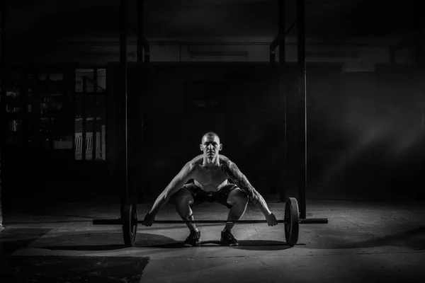 Homme athlétique soulève haltère dans la salle de gym noir et blanc filte — Photo