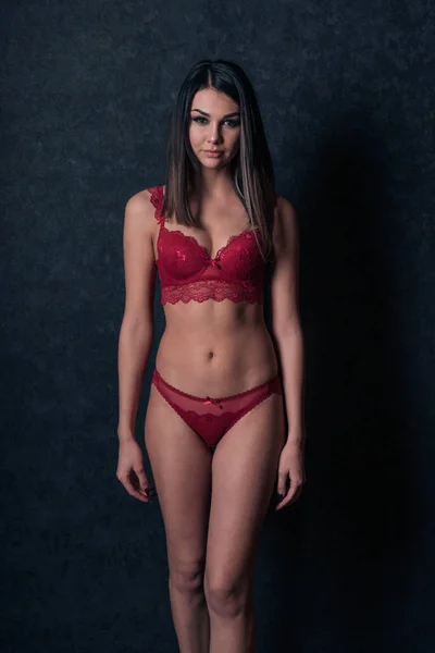 Сексуальная девушка в красном белье стоит у стены — стоковое фото