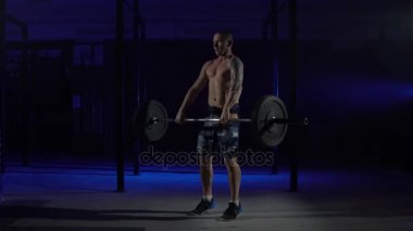 Kaslı bir adam bir halter salonunda göğsüne alır.