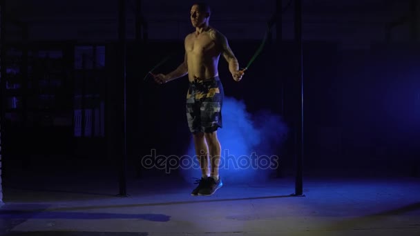 Спортсмен робить подвійні стрибки мотузки в димному тренажерному залі — стокове відео