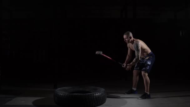 Ισχυρά μυώδες άνθρωπος κτυπά μια βαριοπούλα του ελαστικού στο γυμναστήριο — Αρχείο Βίντεο