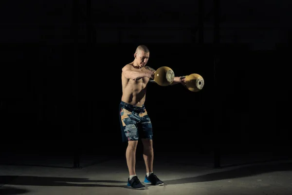 A strong man picks up kettlebell in gym. Kettlebell lifting. Sportlife