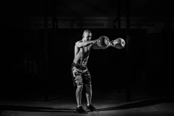 Silny mężczyzna podnosi kettlebell w siłowni. Kettlebell podnoszenia. Czarno-białe poczęcia — Zdjęcie stockowe