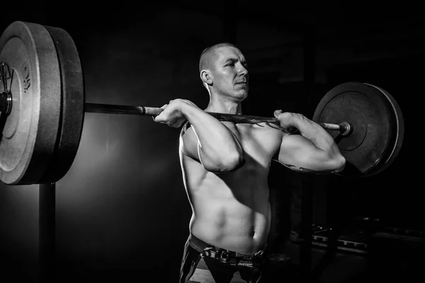 En idrottsman lyfter en skivstång på bröstet i gymmet. BW. idrott — Stockfoto