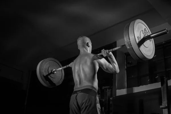 En idrottsman lyfter en skivstång på bröstet i gymmet. BW. idrott — Stockfoto