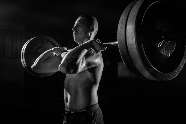 An athlete lifts a barbell on his chest in the gym. bw. sport