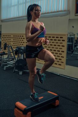 Kardiyo egzersizi. Genç kadın platform için bir step aerobik egzersizleri yapıyor