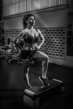 Güzel esmer step aerobik salonunda pratiği yapıyor. BW