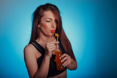 Göz alıcı parlak bir arka plan üzerine soda içen bir esmer kız portresi