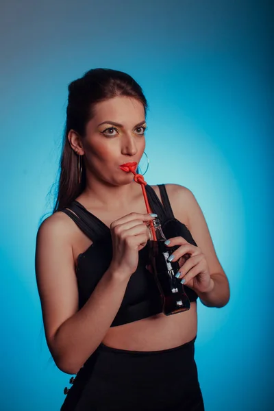 Porträtt av en glamorös vacker flicka, hon dricker en cola på en ljus bakgrund — Stockfoto
