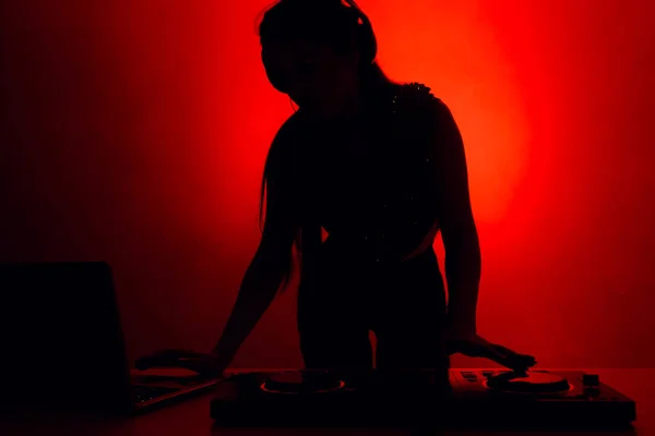 Silueta de una DJ en una fiesta detrás de una consola de música — Foto de Stock