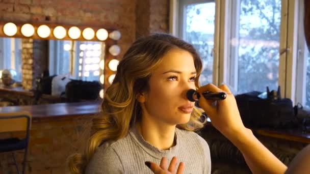 Retrato de una modelo de chica para la que un maquillador hace el maquillaje para una sesión de fotos — Vídeos de Stock