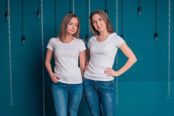 Portret van vriendinnen in witte T-shirts en jeans op een donkere achtergrond — Stockfoto