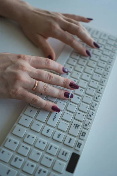 Top view of female hands with beautiful manicure on the keyboard close-up