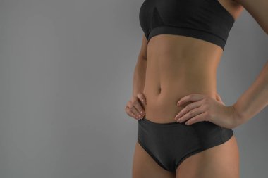 Sexy sportif kadın figürü yakın çekim gri arka plan üzerinde uygun. .