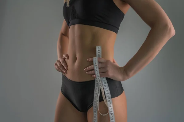 Hermoso cuerpo femenino deportivo sobre un fondo gris — Foto de Stock