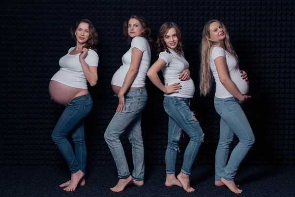 Zwangere vrouwen in witte shirts en jeans op zwarte achtergrond. — Stockfoto
