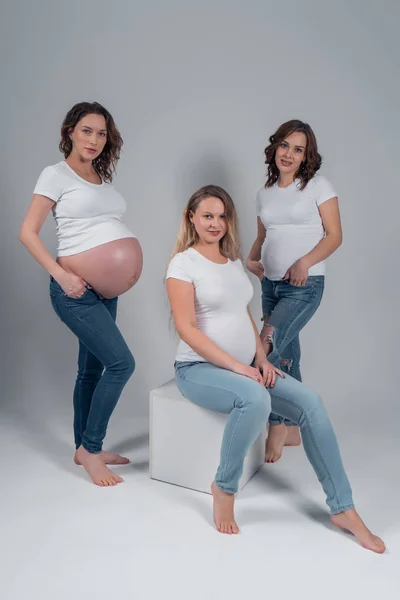 Mulher grávida no estúdio vestindo camisetas brancas e jeans azuis — Fotografia de Stock