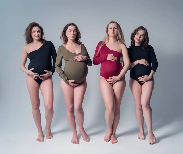 Meninas grávidas jovens em maiôs em um fundo branco . — Fotografia de Stock