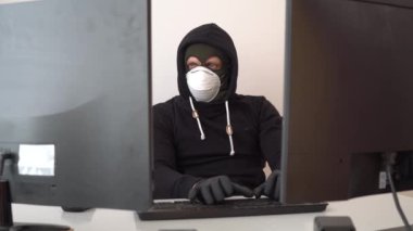Hırsız maskeli ve kapüşonlu adam koronavirüsten korunuyor.