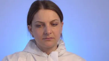 Beyaz koruyucu elbiseli genç bir kadın maske takıyor ve gözlük takıyor..