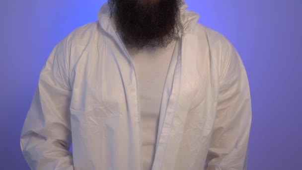 Бородатый мужчина застегивает молнию на защитном белом костюме — стоковое видео
