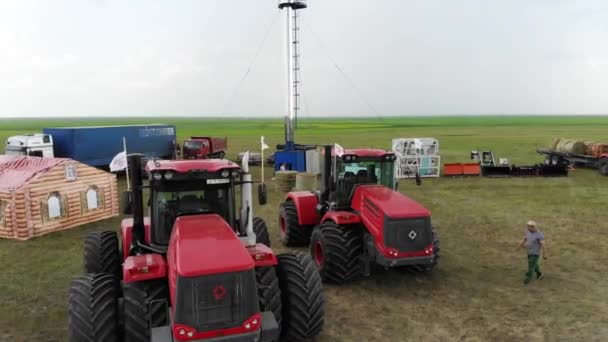 Dois grandes tratores vermelhos estão em exposição no campo . — Vídeo de Stock