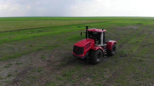 Velký červený traktor na poli v slunečném počasí. — Stock video