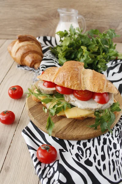 Sandwich de croissant con tocino, queso, lechuga y tomate sobre mesa de madera blanca. Snack saludable . — Foto de Stock