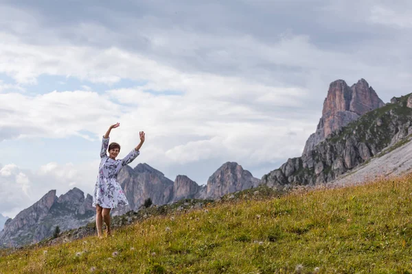 Girl in a dress on a background of mountains. Mountain valley of the Alps, Dolomites. Summer sunny day