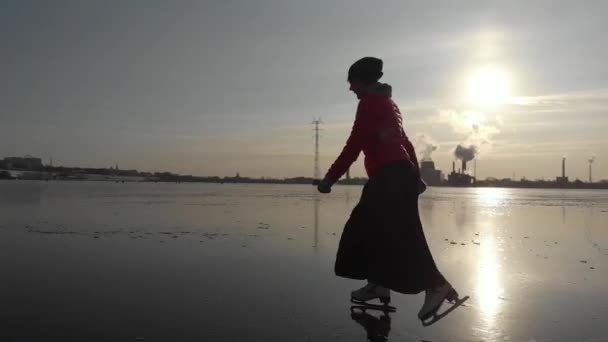 工業都市を背景に大きな貯水池で氷の上でスケート女の子 — ストック動画