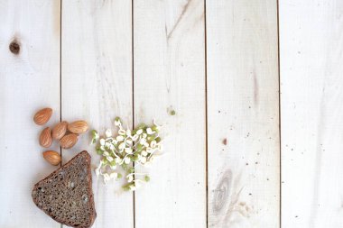 Sağlıklı yiyecek, ekmek, fındık ve filizlenmiş fasulye, ahşap bir ekolojik arka plana yayılmış.